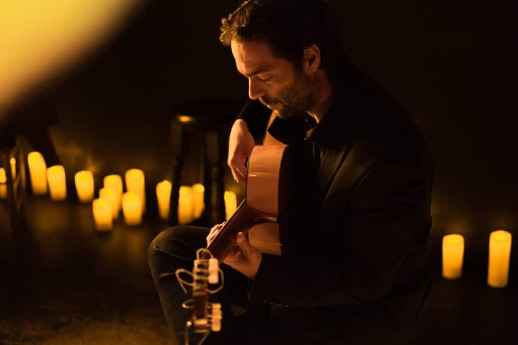 Photo d'un homme jouant de la guitare pour un concert Candlelight entouré de bougies
