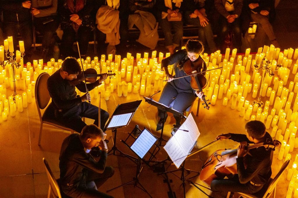Photo d'un concert Candlelight à la bougie en contre plongé et des 4 musiciens formant un quatuor à cordes.
