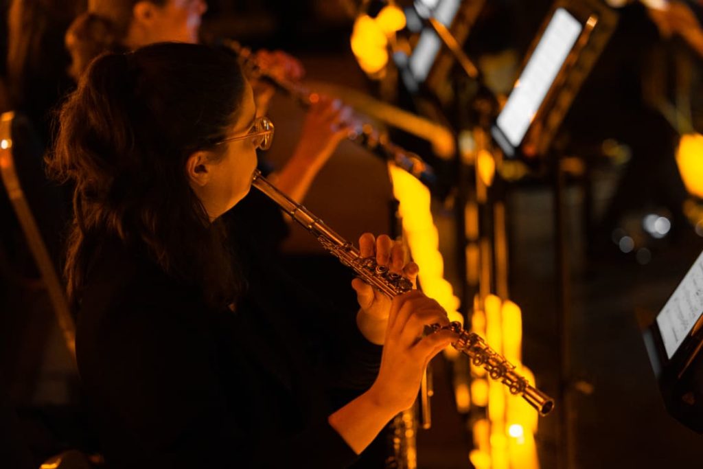 Photo d'une femme jouant de la flute traversière lors d'un concert Candlelight entourée de bougies