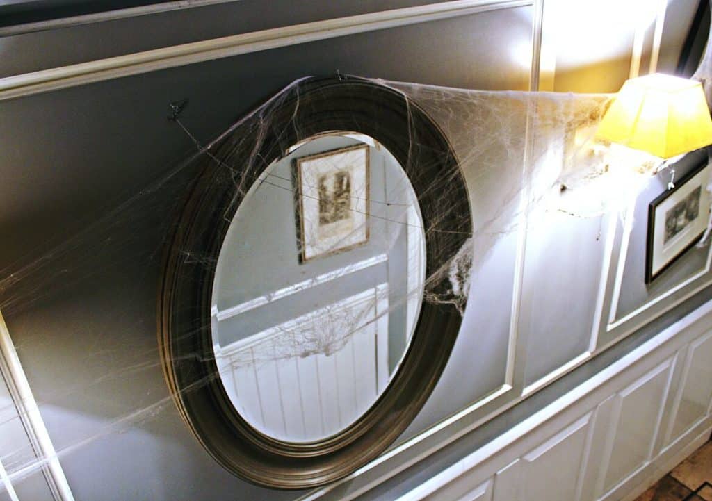 Photo en gros plan d'un mirroir dans un couloir rempli de toile d'araigné éclairé par une lampe au mur pour illustrer un des lieux hantés de Lyon